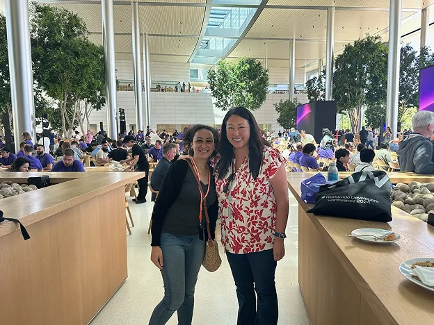 Sylvia Said poses with a woman from Apple's Women's Network in a sunlit Apple Park atrium