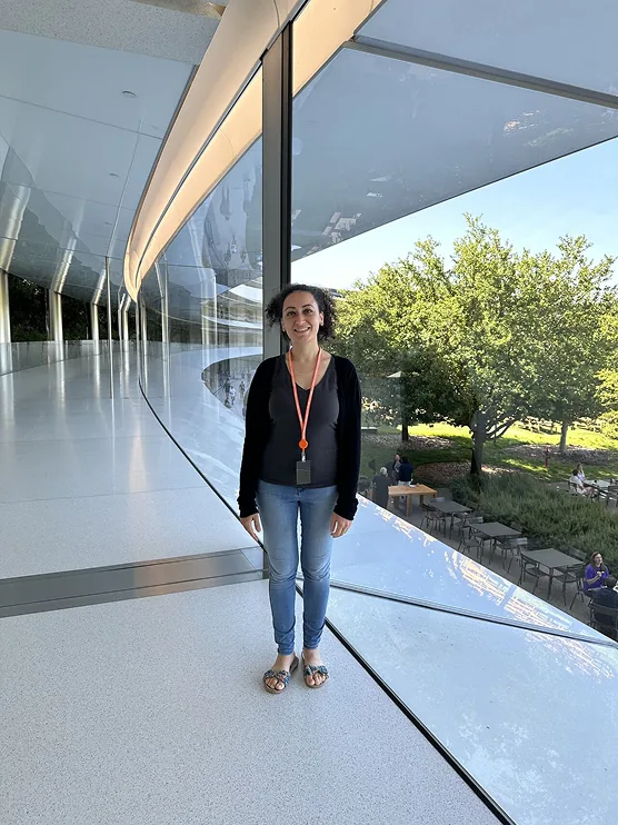 مروج Apple Park بطاولات نزهة ومظلات وقوس مسرح قوس قزح بينما يمشي حضور WWDC