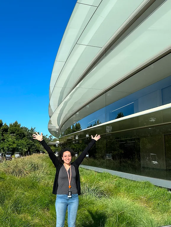 سيلفيا واقفة في الممر الزجاجي المنحني داخل Apple Park